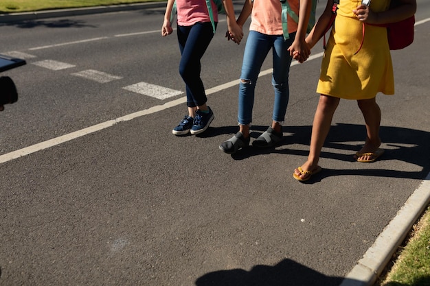 A group of elementary school children participating in a pedestrian safety training session. They are practicing crossing a street with a mock crosswalk and traffic lights, guided by a police officer or safety instructor.
