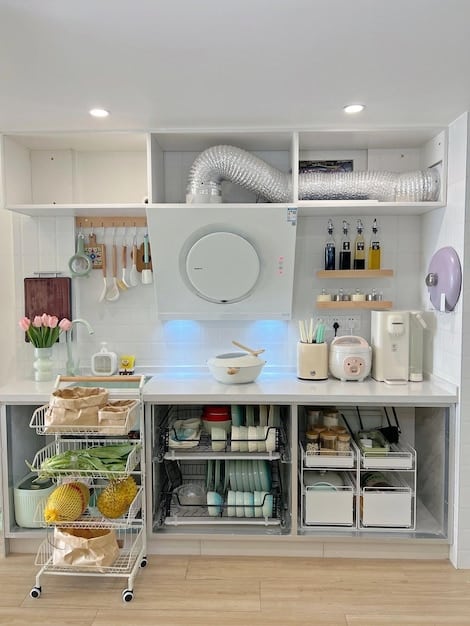 A well-organized and decluttered kitchen featuring stainless steel appliances, a clean countertop, and a small herb garden on the windowsill. The scene is bright, airy, and emphasizes functionality and cleanliness.