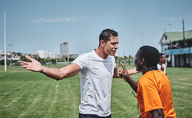 A volunteer coach high-fives a player as they come off the soccer field during a game. The player is smiling and appears proud of their performance. The background shows supportive parents cheering from the sidelines.