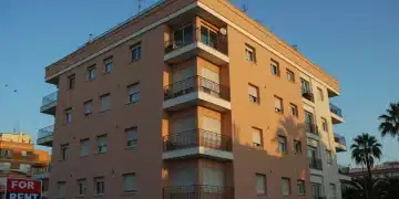 Edificio moderno de apartamentos en España con cartel de alquiler, simbolizando los cambios en la inversión inmobiliaria.