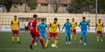 Jugadores de fútbol amateur español en acción durante un partido importante, reflejando la emoción y el dinamismo del deporte local.