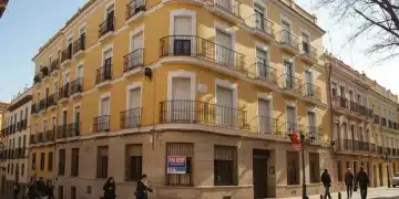 Edificio de apartamentos moderno y atractivo en una ciudad española, con un cartel de 'Se Alquila' visible.