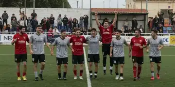 Equipo deportivo comunitario celebrando una victoria, con aficionados animando y un ambiente de alegría.
