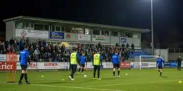 Estadio de club deportivo local vibrante con atletas y aficionados, simbolizando éxito financiero y crecimiento comunitario en 2026.