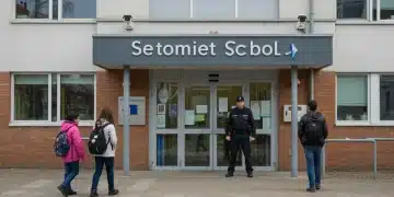 Entrada de una escuela moderna con medidas de seguridad avanzadas y personal de vigilancia en España.